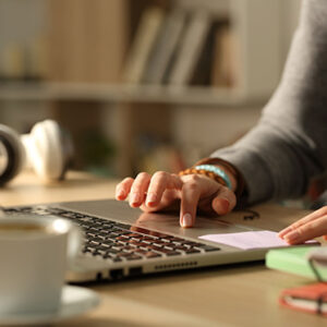Close up of students hands using laptop studying the online real estate course