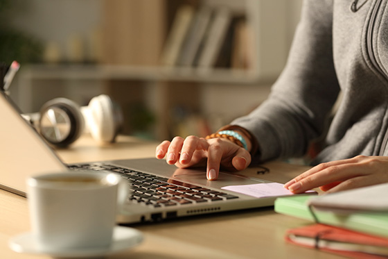 Close up of students hands using laptop studying the online real estate course